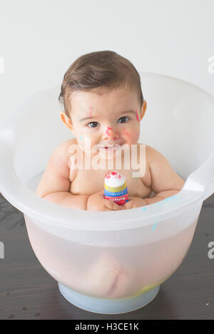 Baby sitting in bagno con tubo di sapone colorate Foto Stock