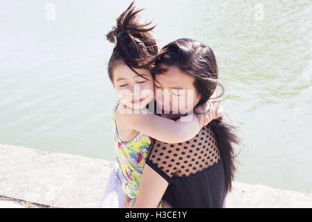 Madre e figlia che abbraccia all'aperto Foto Stock