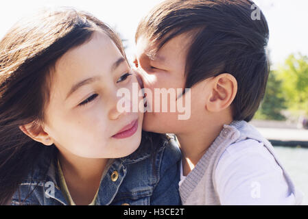 Little Boy baciare la sorella guancia Foto Stock