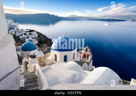 La cittadina di Oia sull isola di Santorini, Grecia. Tradizionale e famose case e chiese con le cupole blu sulla Caldera, il Mare Egeo Foto Stock