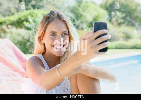 Donna che utilizza smartphone di piscina Foto Stock