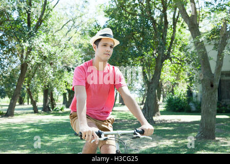 Giovane uomo Bicicletta Equitazione attraverso il paesaggio boscoso, Foto Stock