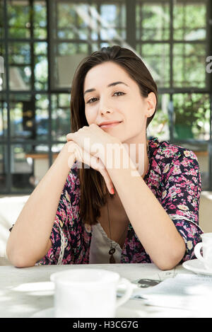 Giovane donna al tavolo per la colazione all'aperto Foto Stock