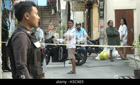 Un Thai funzionario di polizia sorge sul sito di un'esplosione lungo con i residenti locali in Hua Hin, Thailandia. Una serie di blasti coordinato attraverso il sud della Thailandia inclusi Hua Hin e Phuket uccidendo almeno quattro persone e il ferimento di decine in un periodo di 24 ore. Secondo i rapporti, nessun gruppo ha rivendicato gli attentati ma il sospetto è caduto sulla ribelli separatisti. Foto Stock