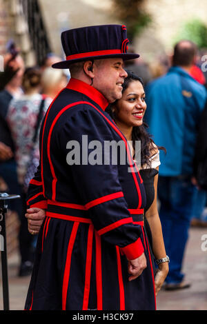 Un Beefeater (Yeoman della guardia) in posa per una fotografia con un turista presso la Torre di Londra, Londra, Inghilterra Foto Stock