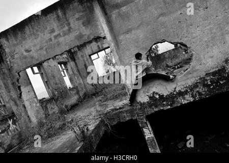 Un colombiano parkour runner salite all'interno di una casa in rovina durante una corsa libera formazione in Bogotá, Colombia. Foto Stock