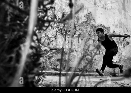 Un colombiano freerunner effettua un salto su un ostacolo durante il parkour sessione di formazione di Bogotá, in Colombia. Foto Stock