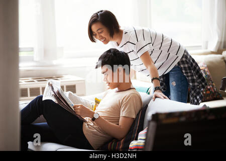 Coppia felice leggendo il giornale in soggiorno Foto Stock