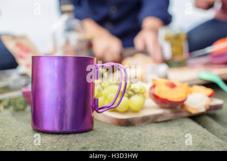 Close-up di viola mug dal vassoio di frutta sulla coperta picnic Foto Stock