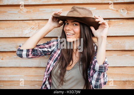 Primo piano della felice bella giovane donna cowgirl in hat su sfondo di legno Foto Stock