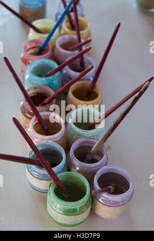 Vetro colorato barattoli di vernice in linea con l'artista spazzole Foto Stock