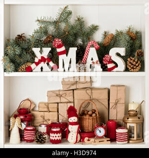 Buon Natale! Lettere di legno XMAS in maglia cappelli e sciarpe in rosso e il colore bianco su uno sfondo di rami di abete con aria cond Foto Stock