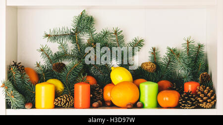 Buon Natale! Sullo sfondo dei rami di abete con pigne, i mandarini e le arance, le candele e i dadi. Messa a fuoco selettiva. Foto Stock