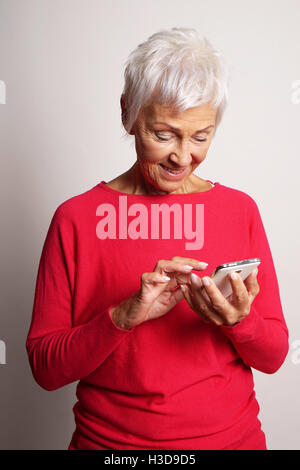 Senior donna utilizza lo smartphone Foto Stock