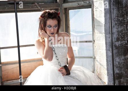 Giovane donna in posa di edificio abbandonato finestra in abito da sposa per la festa di Halloween Foto Stock