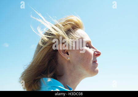 Profilo di una bionda donna matura in piedi dall'oceano. Foto Stock