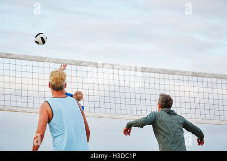 Gli uomini di età matura in piedi su una spiaggia, giocando a pallavolo sulla spiaggia. Foto Stock