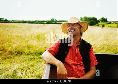 Un uomo in un cappello di paglia seduti nel retro di un pick up truck. Foto Stock