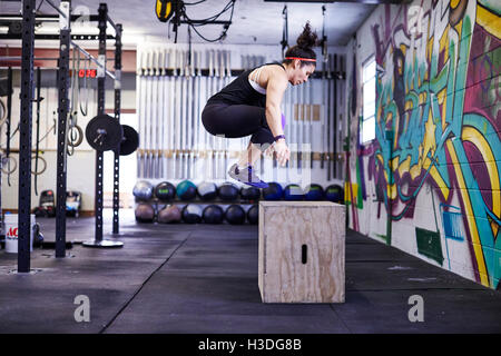 Un atleta femminile treni in una palestra crossfit. Foto Stock