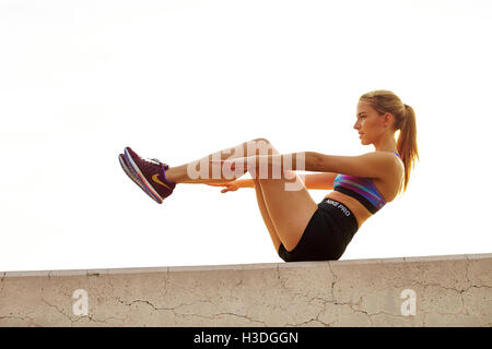 Una giovane donna atletica si allunga. Foto Stock