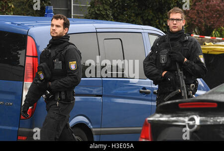 Wettenberg, Germania. Il 7 ottobre, 2016. I funzionari di polizia con mitragliatrici patrol nella parte anteriore del Hells Angels club house di Wettenberg, Germania, 7 ottobre 2016. Il presidente del Hells Angels capitolo regionale è stato ucciso. Foto: BORIS ROESSLER/DPA/Alamy Live News Foto Stock