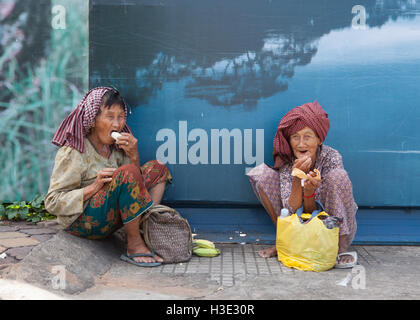 Due donne anziane seduta sul sentiero di mangiare il loro pranzo in Phnom Penh,Cambogia. Foto Stock