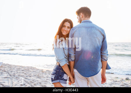 Bella coppia Giovane tenendo le mani e passeggiate in spiaggia Foto Stock