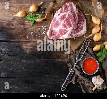 Materie bistecca di carne di maiale cotta sulla carta con lo scalogno cipolla, salsa di pomodoro per la marinata, basilico e condimento, servita con carni forcella ov Foto Stock