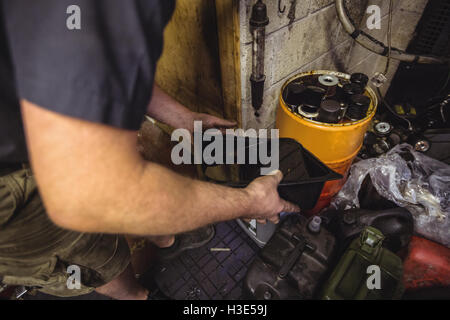 Mechanic versando olio nel possibile Foto Stock