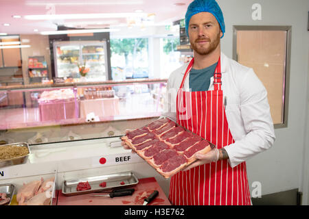 Butcher tenendo un vassoio di bistecche Foto Stock