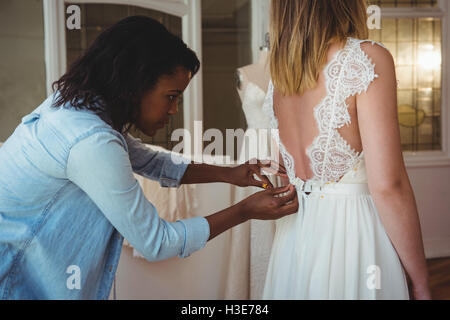 Donna cercando in abito da sposa con il contributo di designer di moda Foto Stock