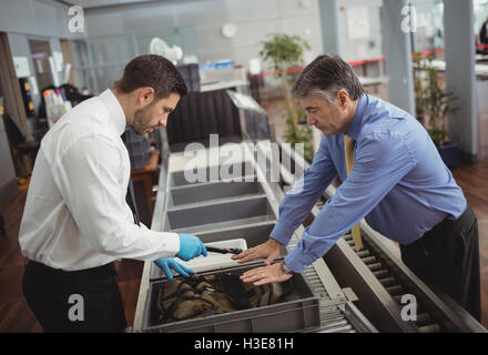 Aeroporto ufficiale di sicurezza utilizzando un rilevatore di metalli per verificare la presenza di un sacchetto Foto Stock