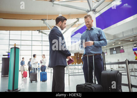 La gente di affari in attesa presso il banco di check-in con il bagaglio Foto Stock