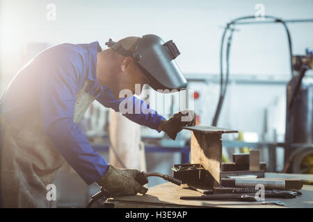 Saldatore maschio esaminando un pezzo di metallo Foto Stock