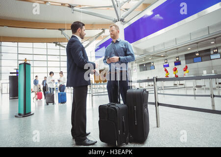 La gente di affari in attesa presso il banco di check-in con il bagaglio Foto Stock