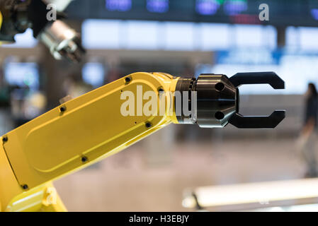 Un giallo il braccio robotico isolata su uno sfondo sfocato Foto Stock