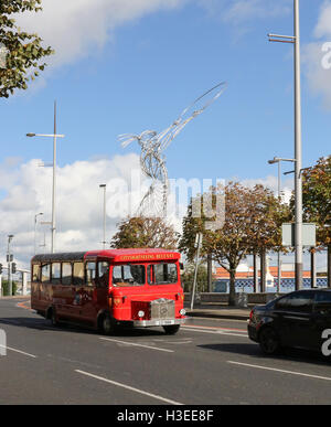 Red single decker City Sightseeing Bus in Belfast, a Oxford Street, Belfast, Irlanda del Nord con la statua di ringraziamento in background. Foto Stock