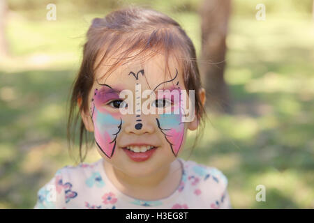 Ragazza carina ottenendo faccia dipinta come una farfalla Foto Stock