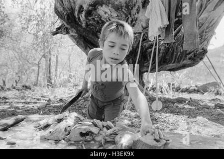 Chalatenango, EL SALVADOR, Giugno 1982: - all'interno del FPL Guerrilla zone di controllo - Un ragazzo visceri di pesce pescato nel lago vicino Cuscatlan. Foto Stock