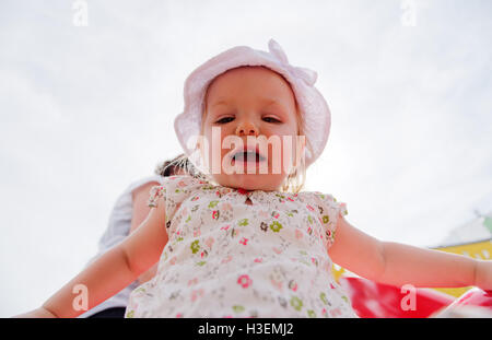 Guardando verso l'alto un sorridente ragazza giovane (2 yr old) vestita di bianco vestiti estivi Foto Stock