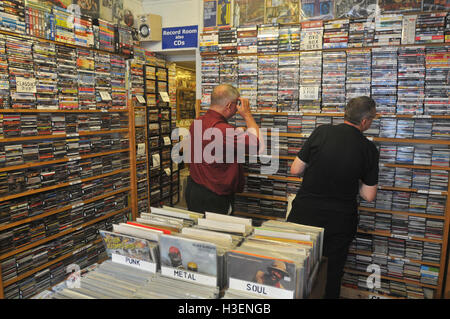 Due persone di mezza età uomini sfoglia il CD rack in un record e DVD shop Foto Stock