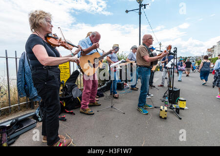 La baia Boys, musicale folk gruppo di alti uomini la riproduzione di chitarre nel sole, insieme con una donna fiddle player, un concerto sul lungomare. Foto Stock