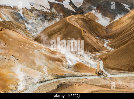 Kerlingarfjoll, Islanda - 3 Luglio 2016: Fiume con il rosso delle colline e il rosso e il nero della lava montagne innevate in Kerlingarfjoll in Islanda Foto Stock