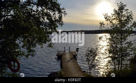 Il molo di legno sul lago con il bagnato orme Foto Stock