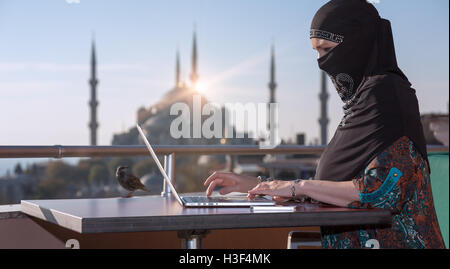 Tradizionalmente Vestiti donna musulmana lavorando sul computer Foto Stock