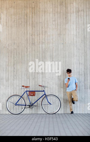 Uomo con lo smartphone e fixed gear bike su strada Foto Stock