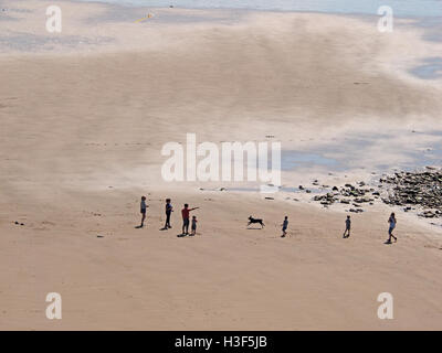 Guardando verso il basso in corrispondenza di una famiglia con cane in esecuzione sulla pittoresca spiaggia di St api Cumbria in bianco e nero Foto Stock