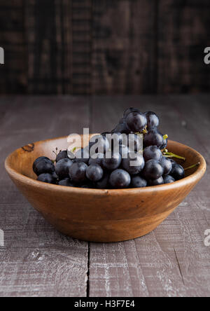 Fresche uve sane in ciotola di legno su sfondo di legno Foto Stock