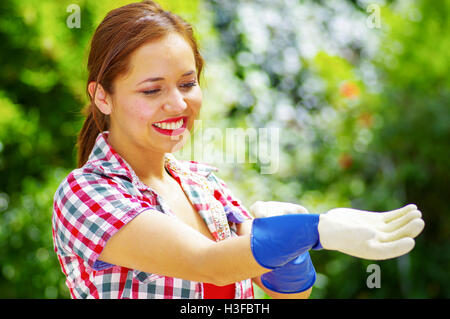 Le donne con una maglietta colorfull mettendo sul guanti Foto Stock