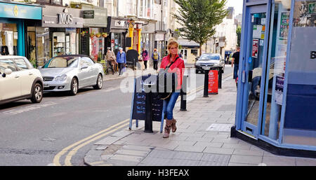 Donna che indossa giacca rossa e jeans moda passeggiate in St James Street Brighton Regno Unito Foto Stock